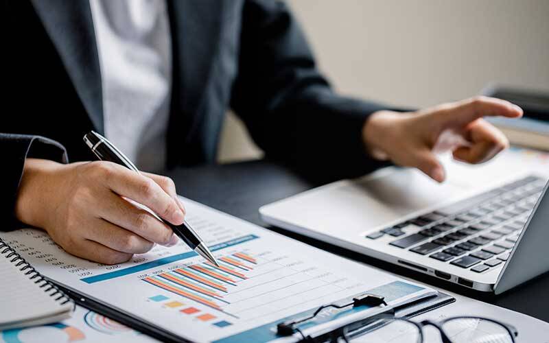 Picture of business man looking at charts and information while using a laptop computer
