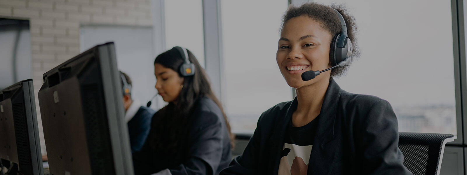 Picture of female office team using desktop computers and wearing headphones