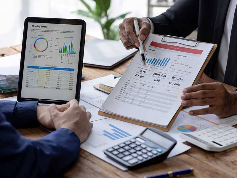 Business men consulting charts and information on printed paper and on the screen of a tablet computer