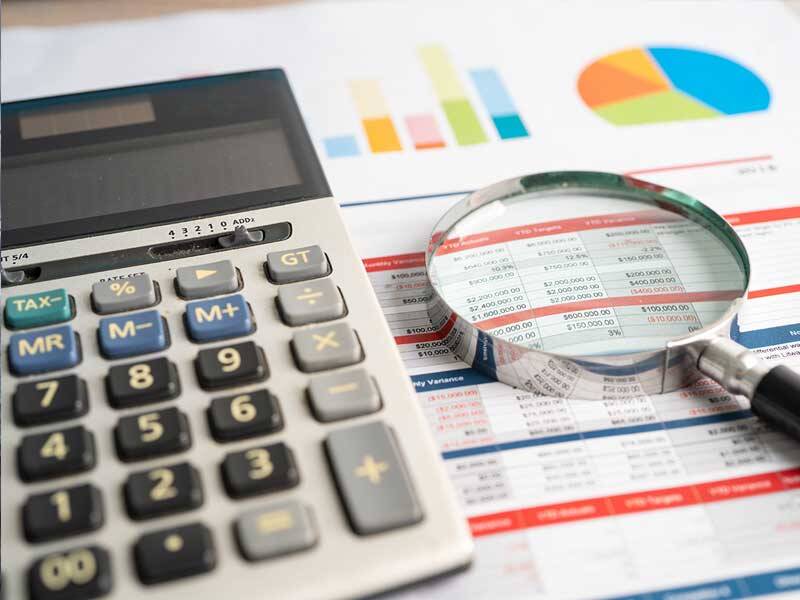 Charts and figures on table with magnifying glass and calculator