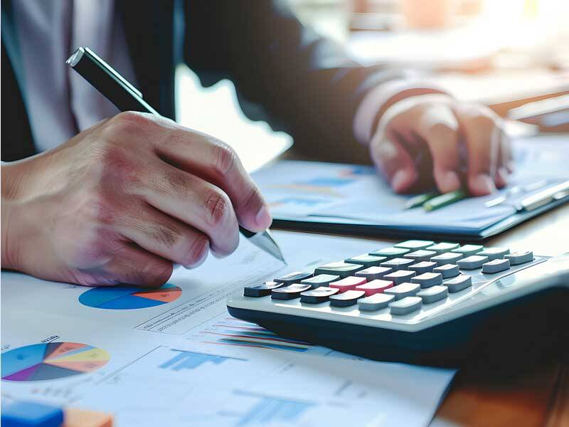 Business man looking at charts and information on paper and using a calculator