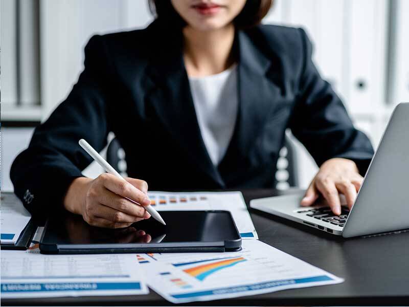 Business touching the screen of tablet computer with a stylus and using a laptop computer
