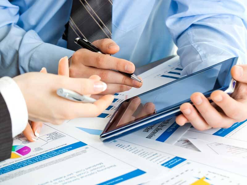 Business men pointing at paperbased charts and infromation and the screen of a tablet computer