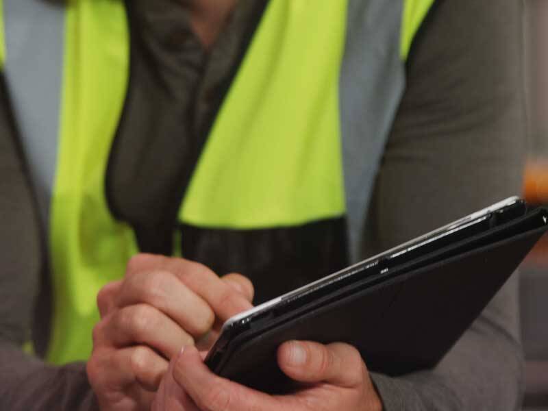 Construction worker wearing high-visiability vest and looking at a clip board
