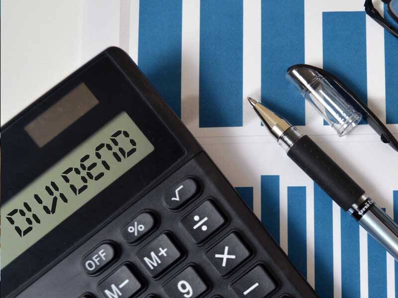 Charts and figures with calculator showing the word Dividend on the screen
