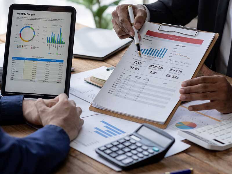 Business men looking at charts and figures on paper and on the screen of a tablet computer