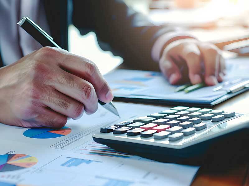 Business man looking at paper based charts and figures and using a calculator