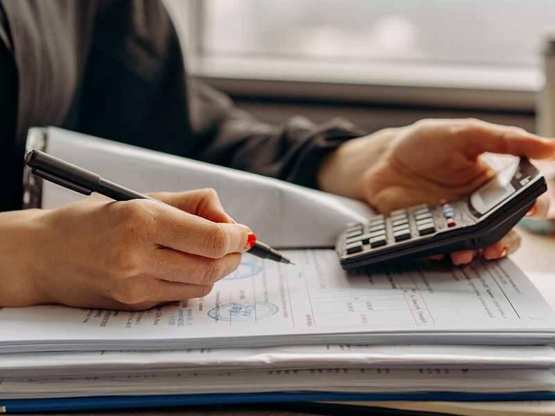 Business woman using a calculator and reviewing invoices in a lever arch folder