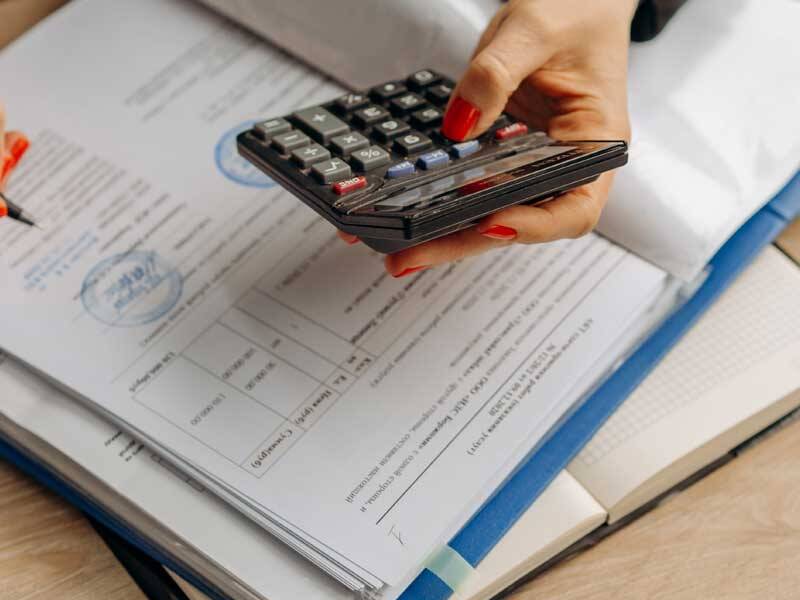 Business woman using a calculator and reviewing invoices in a lever arch folder