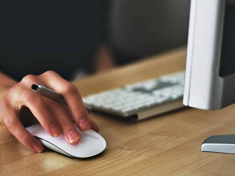 Computer user using a wireless computer mouse and looking at the screen of computer