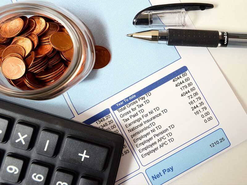 Payslip with calculator and jar of copper coins